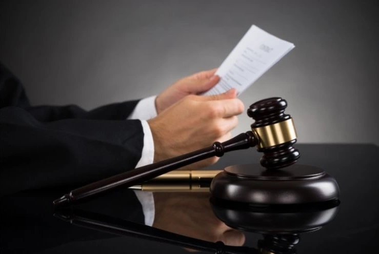 man in suit holding document next to gavel